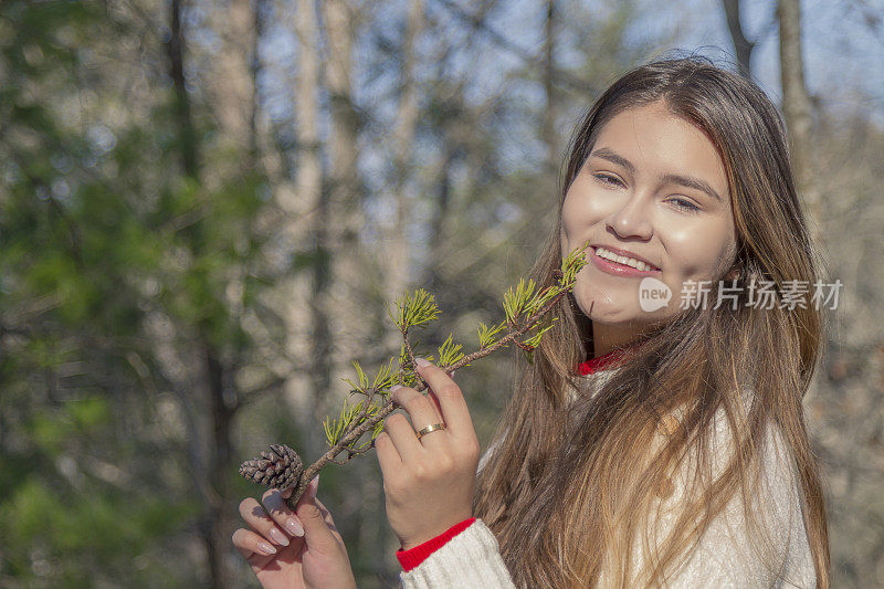 一个寒冷的感恩节/圣诞节秋天的早晨/下午，一位年轻的拉丁妇女在松冠森林中间休息时的画像。